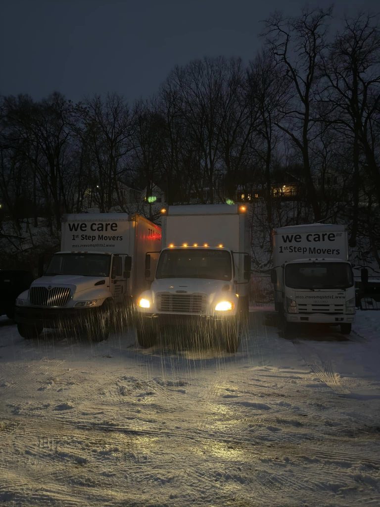 Three 1st Step Movers trucks illuminated at night on a dimly lit road, showcasing the company's expanded fleet.