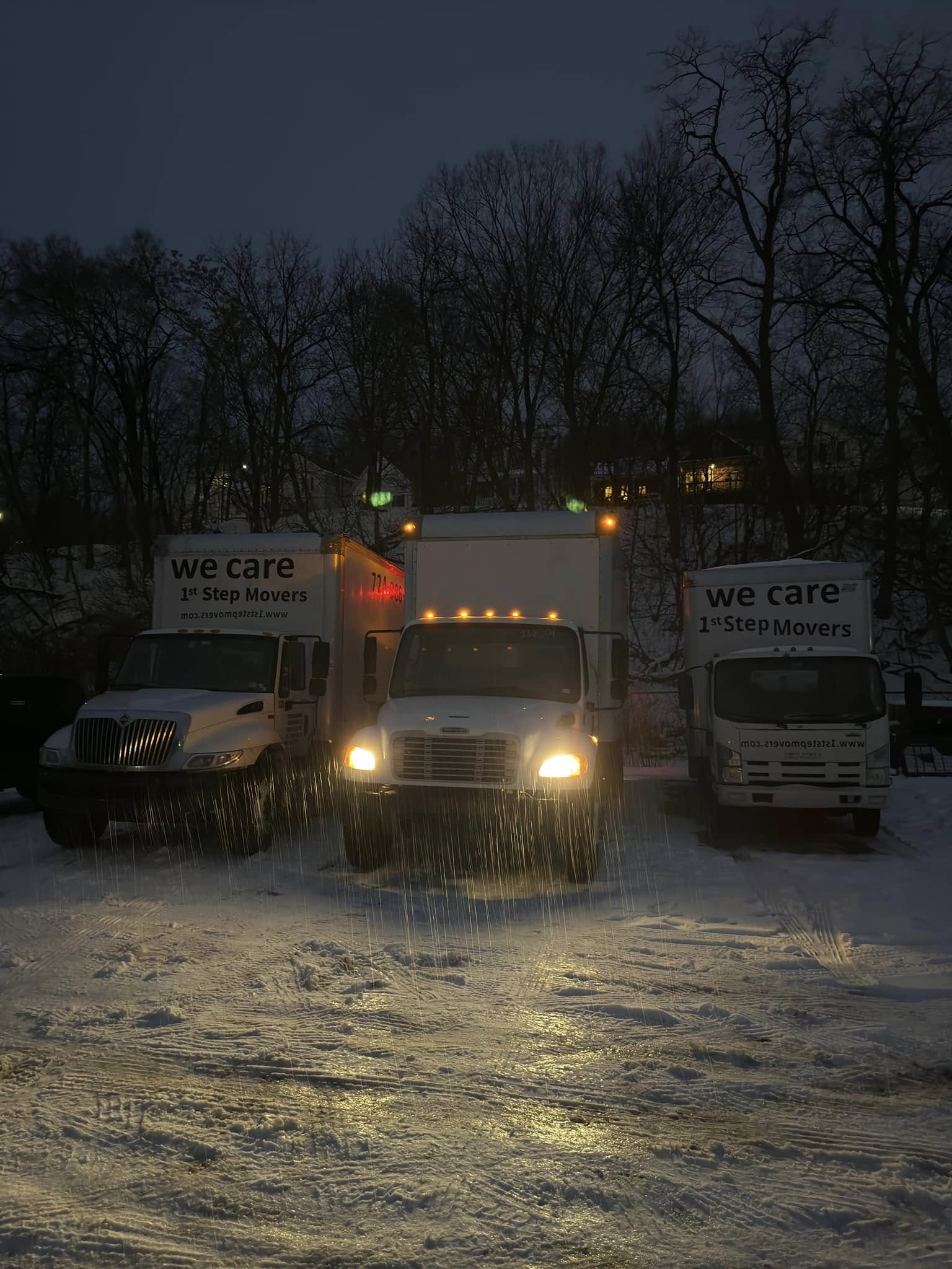 Three 1st Step Movers trucks illuminated at night on a dimly lit road, showcasing the company's expanded fleet.