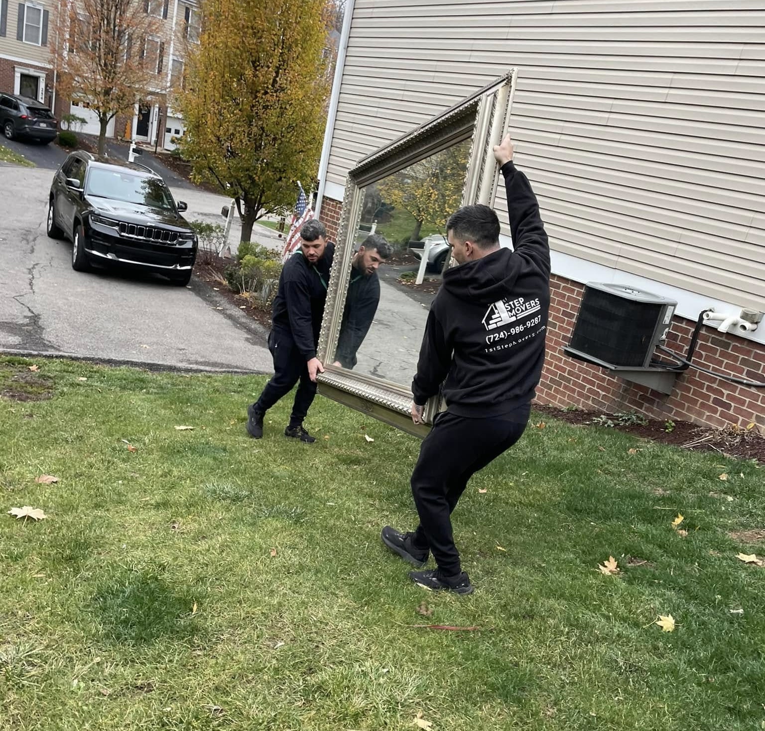 1st Step mover carrying a large framed mirror across a yard