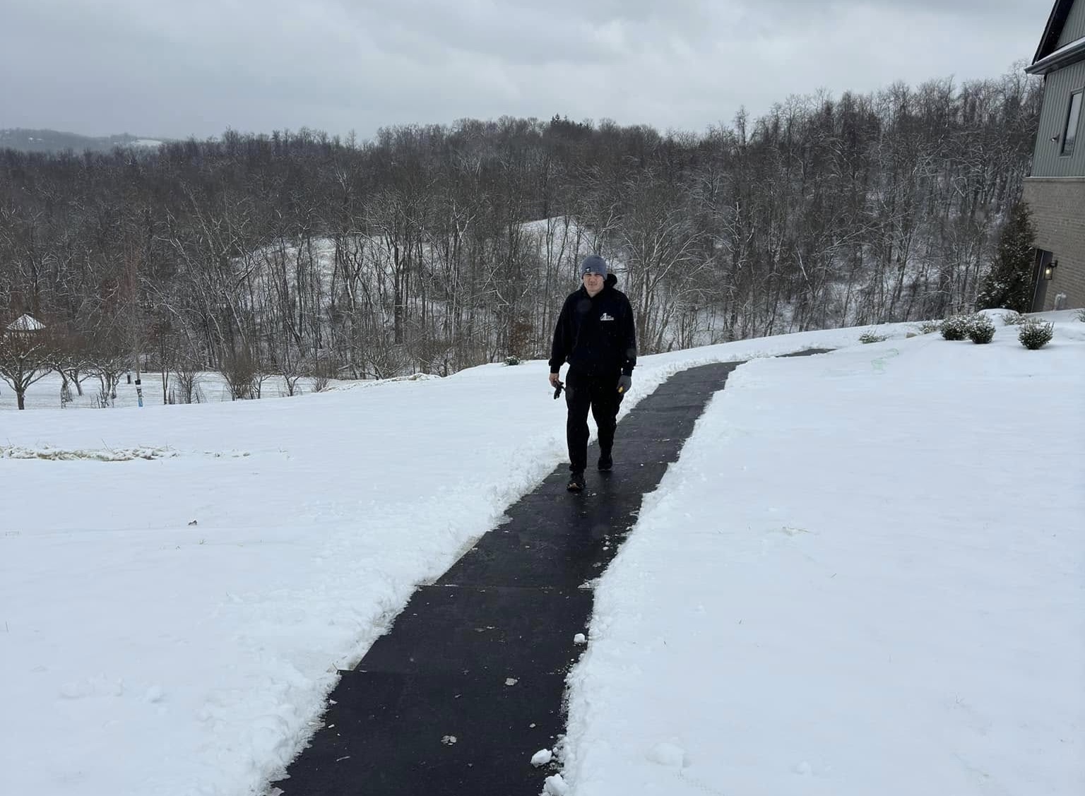 Mover walking a cleared path through snow toward a house